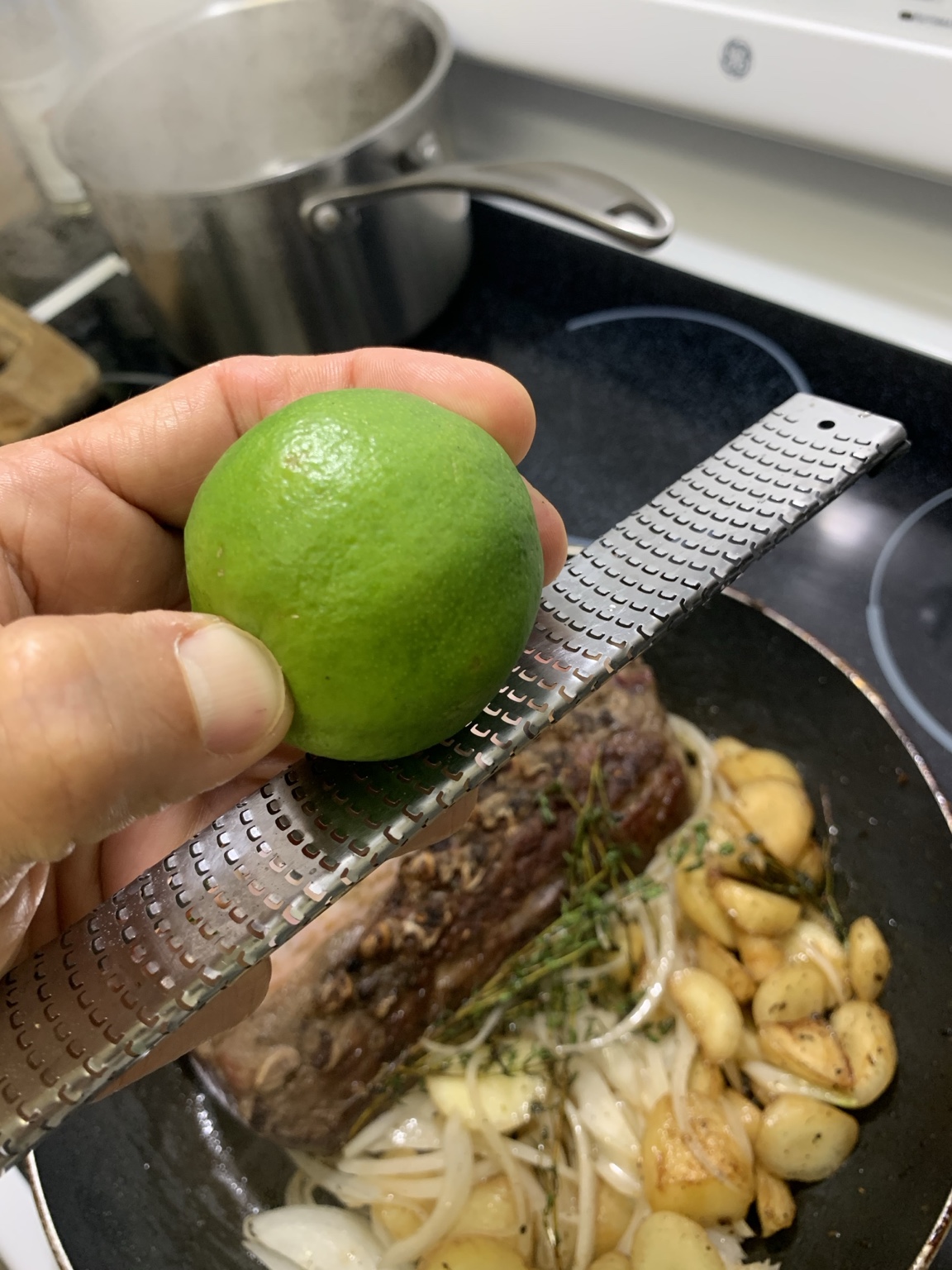 Mano sosteniendo un limón sobre un rallador durante una preparación